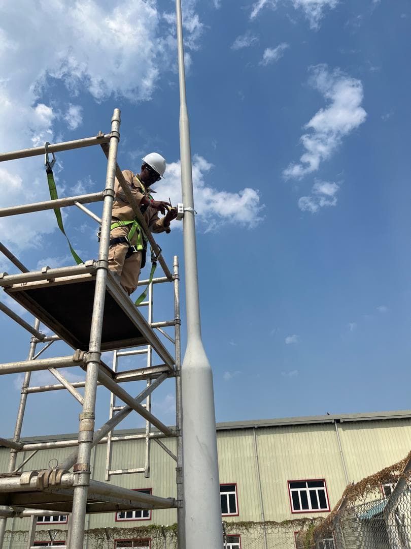 Scaffold-access camera installation on a lighting column at an industrial facility.